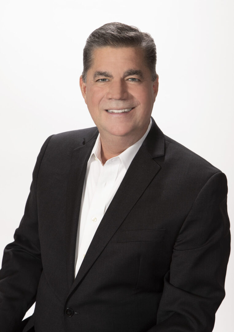 A man in a suit and tie smiling for the camera.